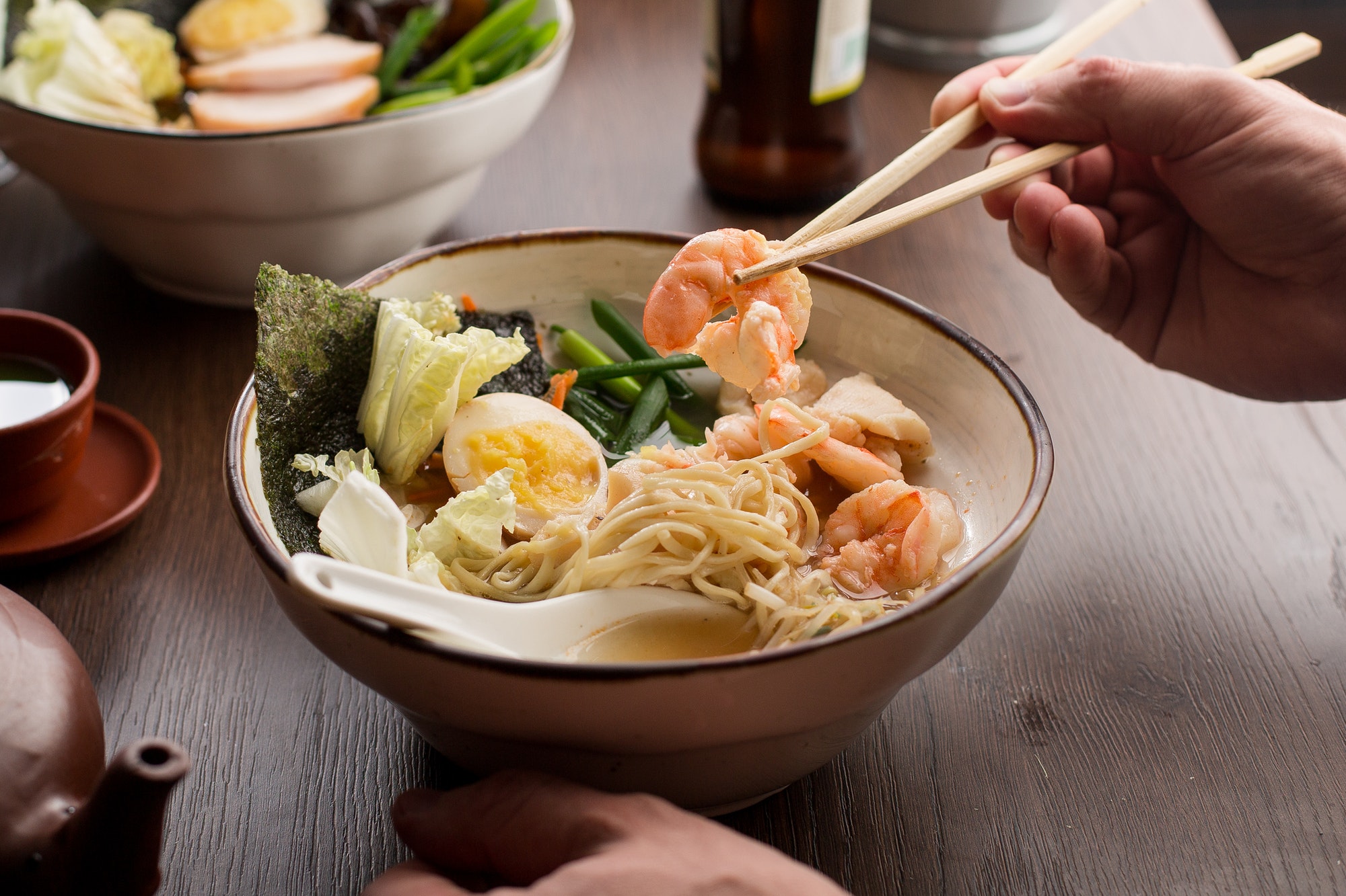 man-eating-asian-ramen-with-shrimps-and-noodles-in-a-restaurant.jpg